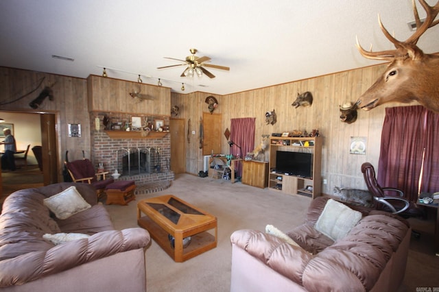 living room with wood walls, a fireplace, ceiling fan, and light colored carpet