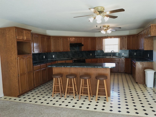 kitchen featuring ceiling fan, a kitchen bar, and a kitchen island