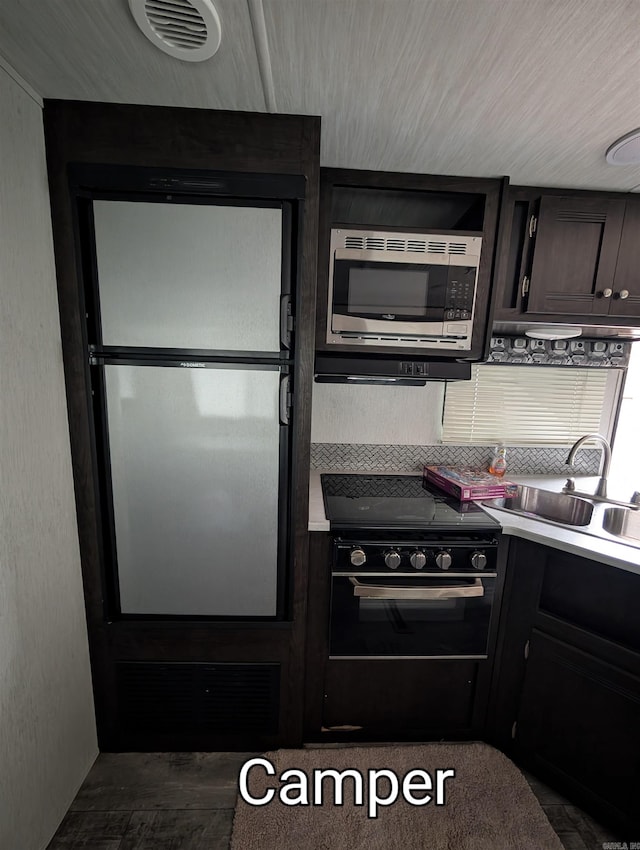 kitchen featuring black electric range, stainless steel microwave, sink, and refrigerator