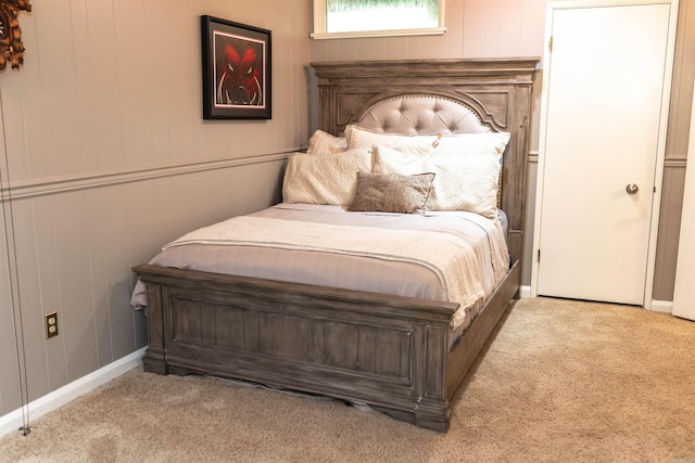 bedroom featuring light colored carpet and wooden walls