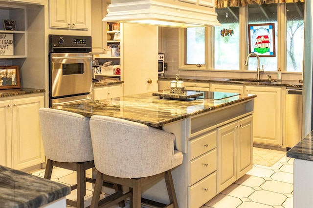 kitchen featuring a breakfast bar, a center island, premium range hood, sink, and stainless steel appliances