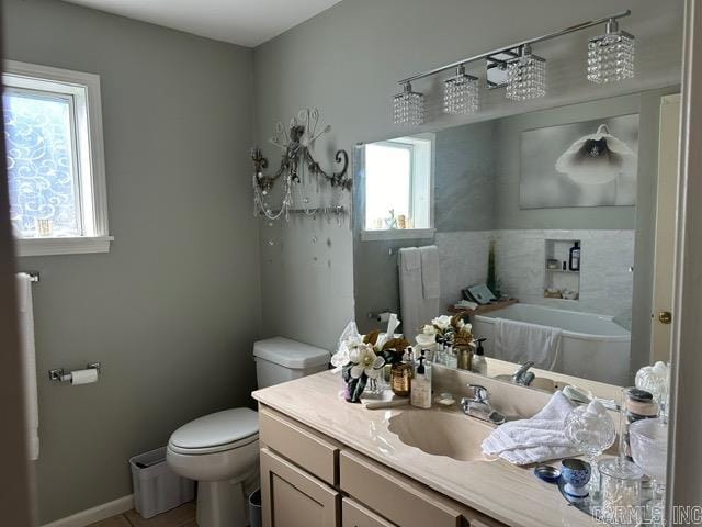 bathroom with toilet, a wealth of natural light, and vanity