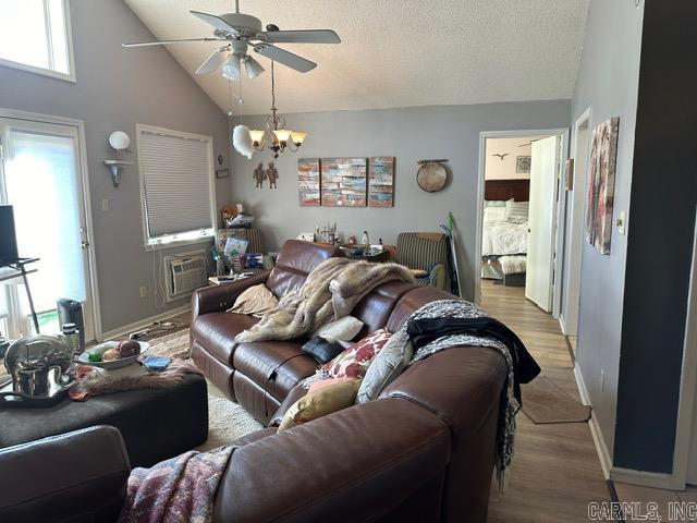 living room featuring light hardwood / wood-style floors, a textured ceiling, ceiling fan with notable chandelier, and high vaulted ceiling