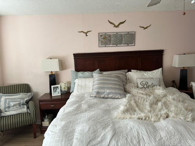 bedroom with ceiling fan, hardwood / wood-style floors, and a textured ceiling