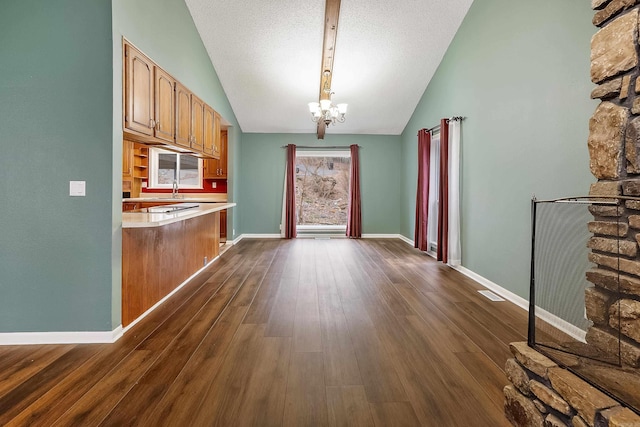 kitchen featuring lofted ceiling, a chandelier, dark wood-type flooring, and a textured ceiling