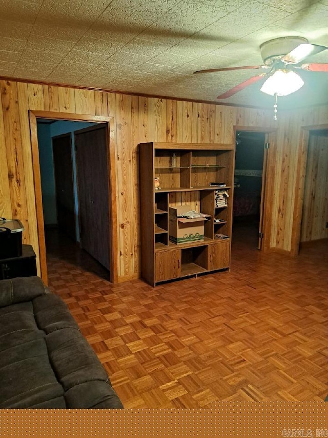 living area featuring wooden walls and ceiling fan