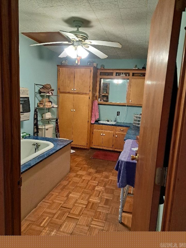 bathroom with a garden tub, a ceiling fan, and a textured ceiling