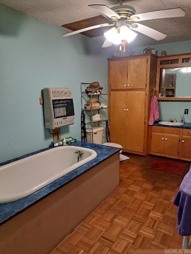 bathroom featuring a ceiling fan, vanity, heating unit, and a bathtub