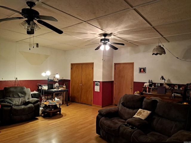 living room featuring ceiling fan, wood finished floors, and wainscoting