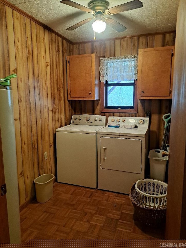 clothes washing area with a ceiling fan, wooden walls, cabinet space, and independent washer and dryer