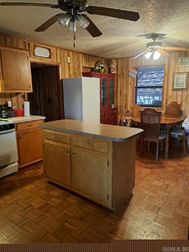 kitchen with gas range, wooden walls, and freestanding refrigerator