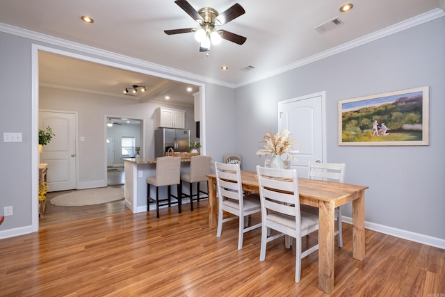 dining space with ceiling fan, ornamental molding, and light hardwood / wood-style flooring