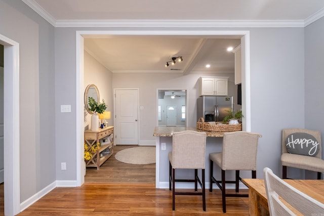 kitchen featuring hardwood / wood-style flooring, ceiling fan, beamed ceiling, white cabinets, and stainless steel fridge