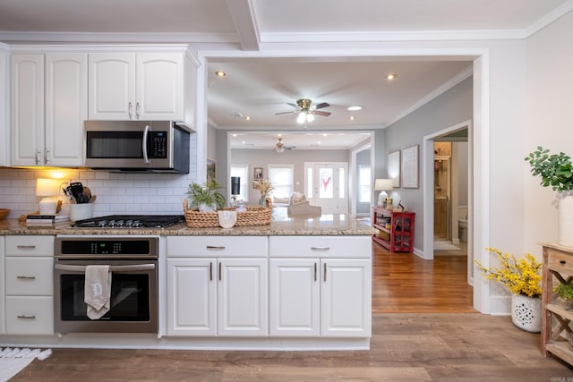 kitchen featuring ceiling fan, stainless steel appliances, light hardwood / wood-style floors, light stone countertops, and white cabinets