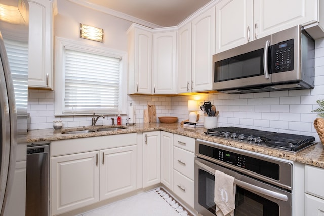 kitchen featuring sink, light stone counters, white cabinets, stainless steel appliances, and tasteful backsplash