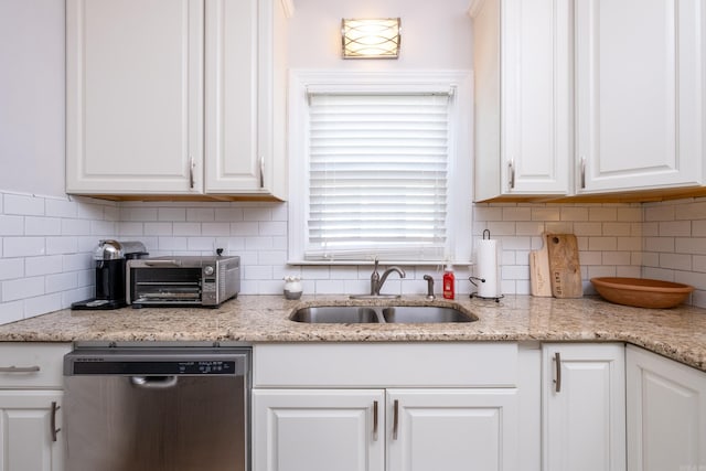 kitchen featuring light stone countertops, backsplash, sink, white cabinets, and dishwasher