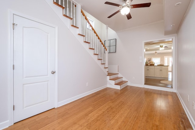 stairs with light hardwood / wood-style flooring, ornamental molding, and ceiling fan