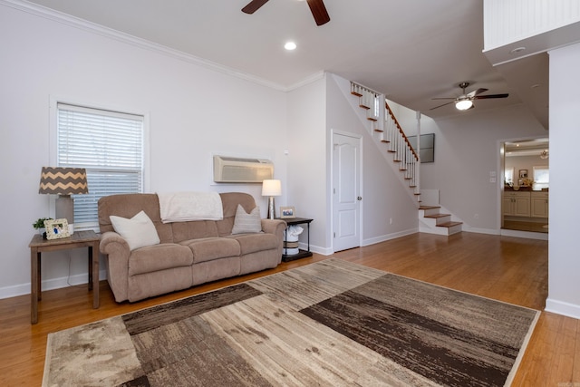 living room with light hardwood / wood-style flooring, an AC wall unit, ceiling fan, and crown molding