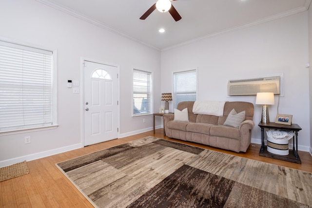 living room with ceiling fan, an AC wall unit, ornamental molding, and light hardwood / wood-style floors