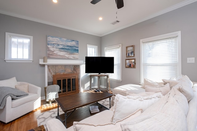 living room with a wealth of natural light, light hardwood / wood-style floors, ceiling fan, and a fireplace