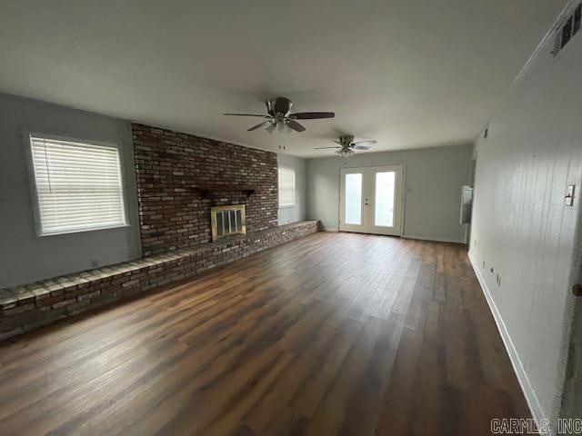 unfurnished living room featuring dark hardwood / wood-style flooring, french doors, a brick fireplace, brick wall, and ceiling fan