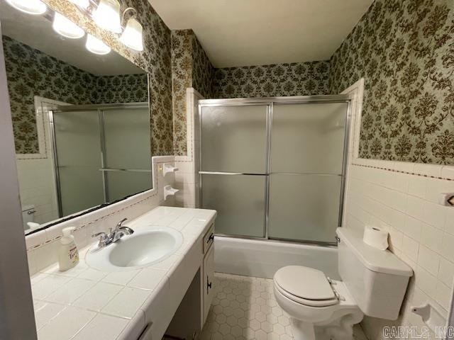 full bathroom featuring tile walls, tile floors, bath / shower combo with glass door, toilet, and vanity