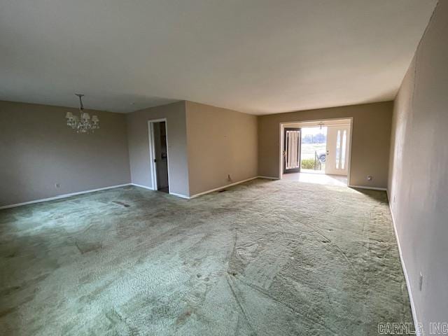 carpeted spare room with a chandelier