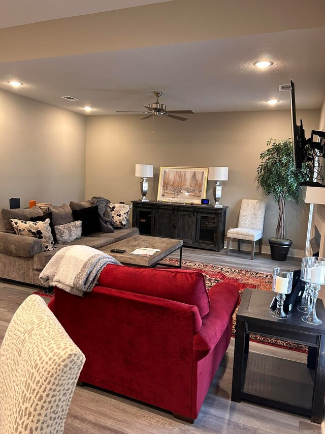 living room featuring ceiling fan, wood-type flooring, and a fireplace