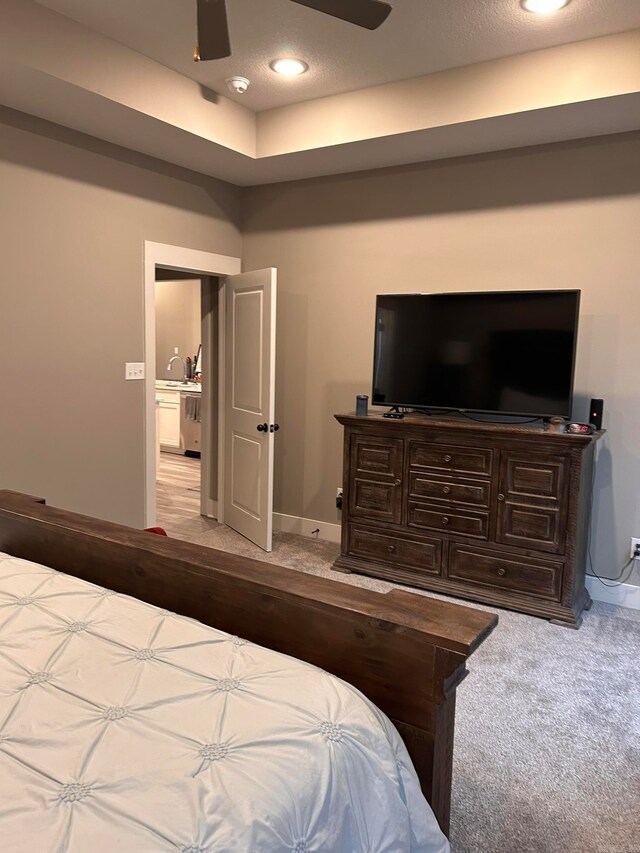 bedroom with ceiling fan, sink, and light colored carpet