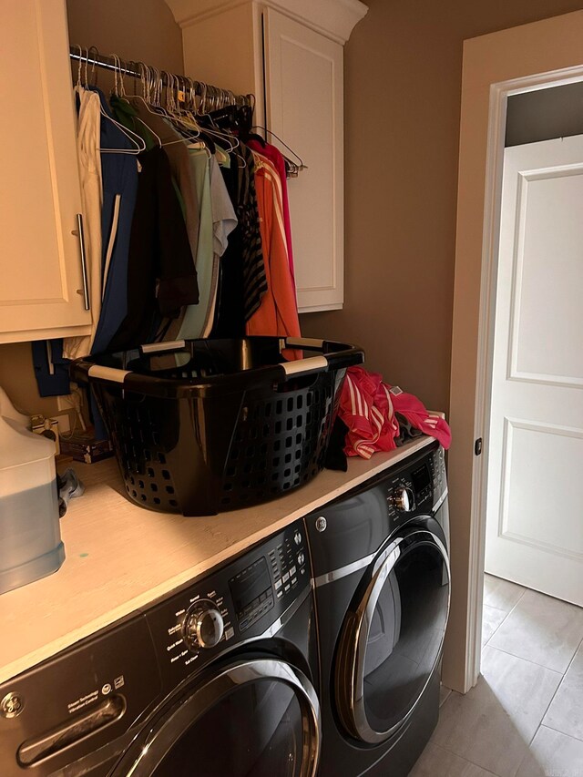 clothes washing area with tile flooring, cabinets, and washer and dryer