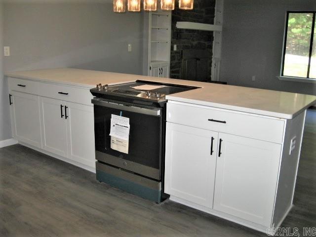 kitchen with kitchen peninsula, electric range, dark hardwood / wood-style flooring, white cabinets, and a fireplace