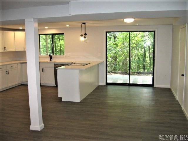 kitchen with pendant lighting, dark wood-type flooring, backsplash, kitchen peninsula, and white cabinetry