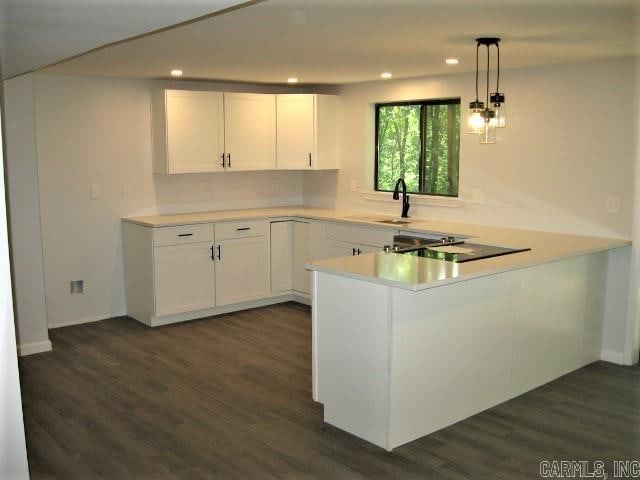 kitchen featuring white cabinets, kitchen peninsula, dark hardwood / wood-style flooring, and pendant lighting