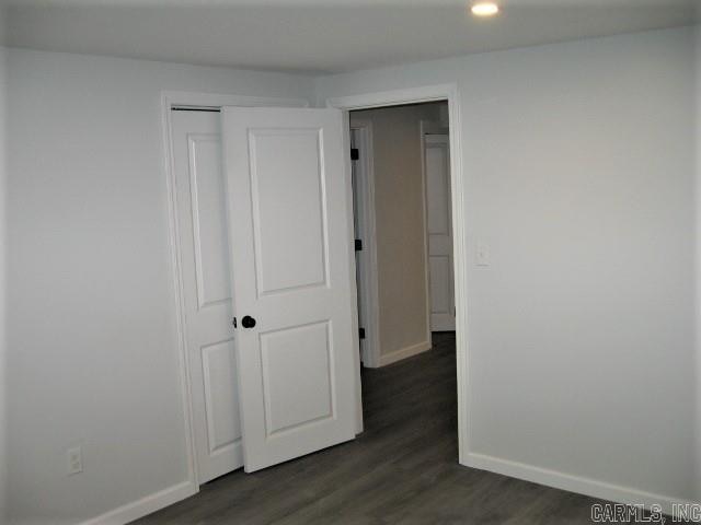 unfurnished bedroom featuring a closet and dark wood-type flooring