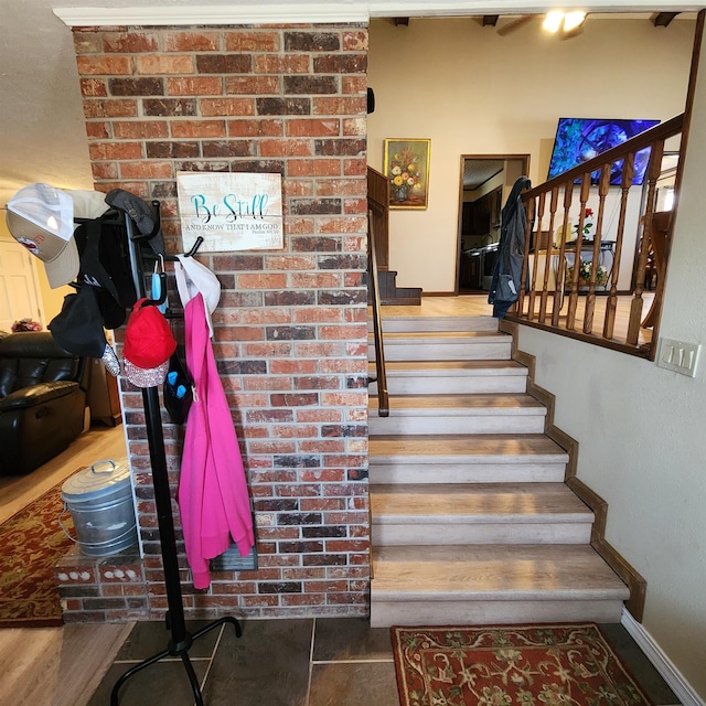 stairs featuring brick wall and hardwood / wood-style flooring