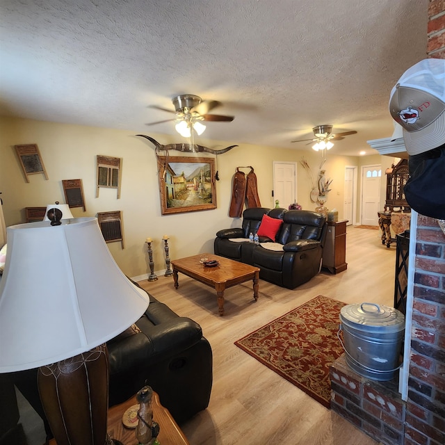 living room featuring a textured ceiling, ceiling fan, and light wood-type flooring