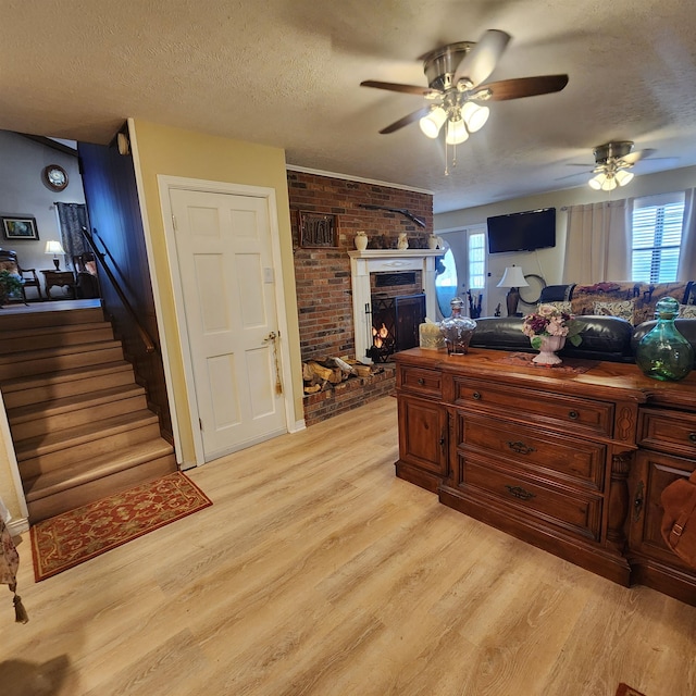 living room with ceiling fan, a brick fireplace, and light wood-type flooring