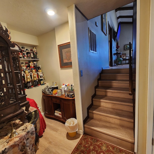 staircase featuring a textured ceiling and light wood-type flooring