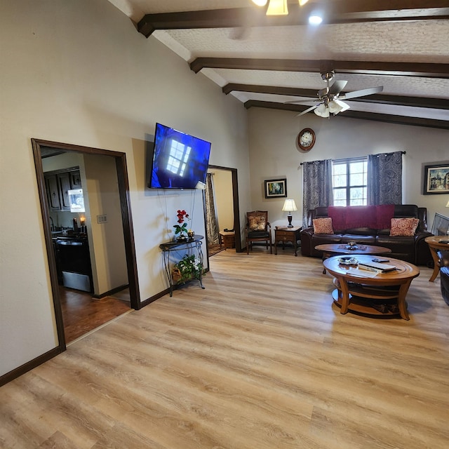 living room with ceiling fan, vaulted ceiling with beams, and light hardwood / wood-style floors