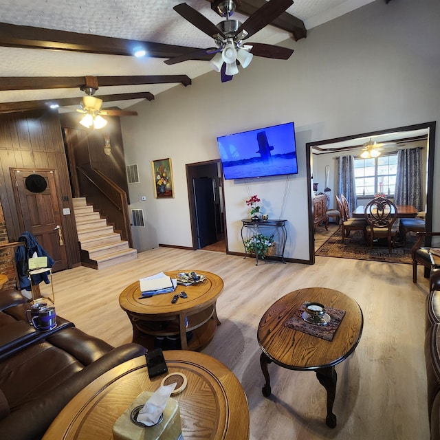 living room featuring light hardwood / wood-style floors, ceiling fan, and beamed ceiling