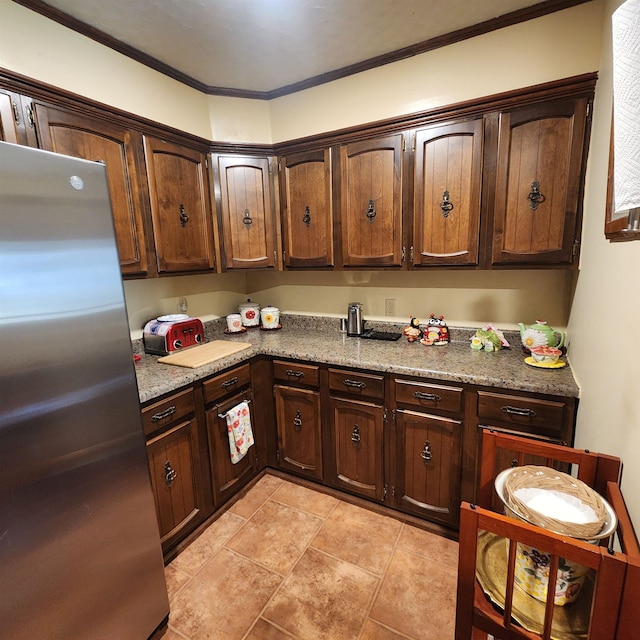 kitchen with light tile flooring, stone countertops, dark brown cabinets, crown molding, and stainless steel fridge