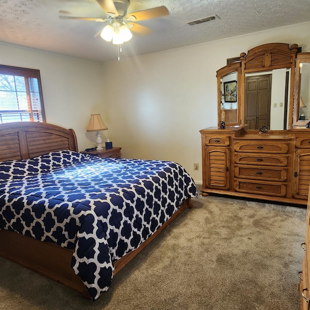 bedroom with a textured ceiling, ceiling fan, and carpet