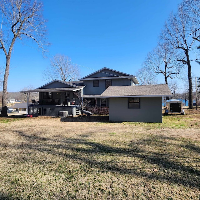 rear view of property with central AC and a yard