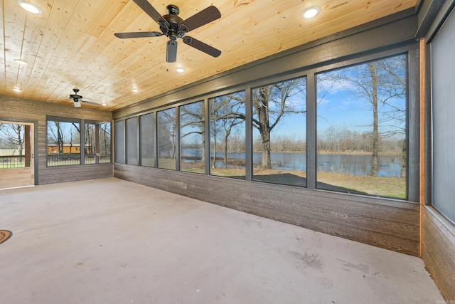 unfurnished sunroom featuring ceiling fan, wooden ceiling, and a water view