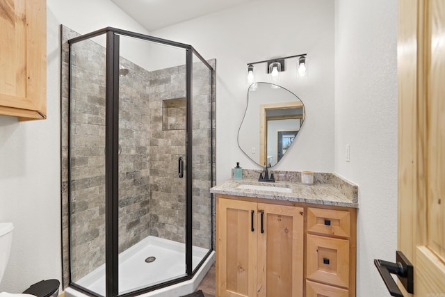 bathroom with a shower with shower door, vanity, and toilet