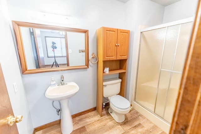 bathroom featuring a shower with door, wood-type flooring, and toilet