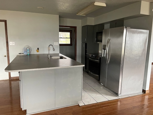 kitchen featuring range, stainless steel fridge, sink, and light tile flooring