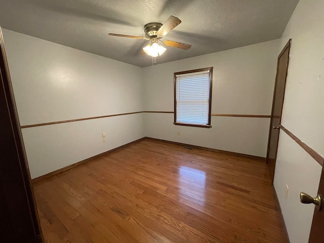 unfurnished room featuring ceiling fan, hardwood / wood-style flooring, and a textured ceiling