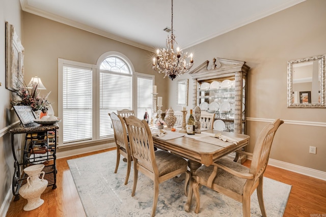 dining area with a notable chandelier, crown molding, and light hardwood / wood-style floors