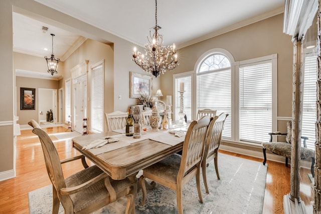 dining area featuring a notable chandelier, crown molding, and light wood-type flooring